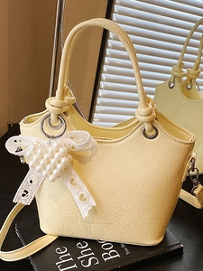 Fashionable pale yellow pleated bucket bag with pearl heart charm and knotted top handle