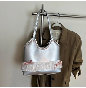 Close-up of silver tote bag with pink scalloped trim and white lace bow details