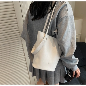 White bucket bag with crocodile pattern worn by a model in a casual street style look