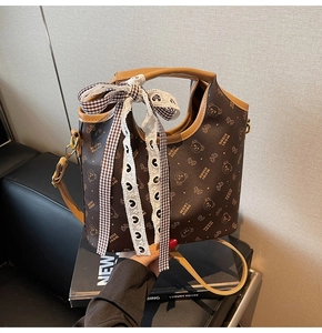 Close-up of brown bucket bag featuring bear prints, lace bow, and lychee leather texture