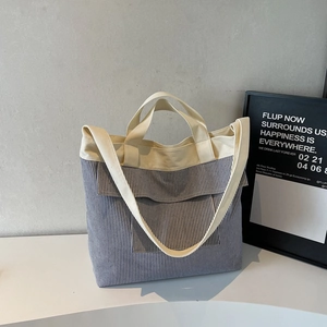 Detail of blue striped canvas tote bag showing front flap pocket and minimalist design