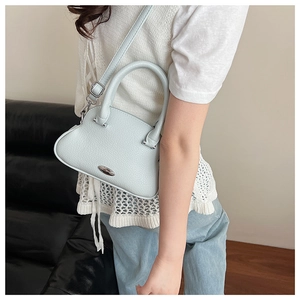 Detail of light blue lychee pattern leather handbag with silver oval metal hardware