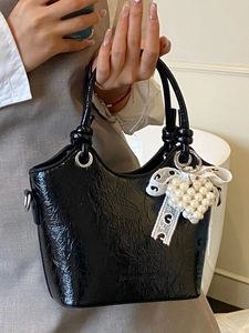 Chic black patent leather bucket bag with wrinkled texture, pearls and lace bow detail