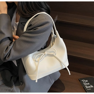 Detailed close-up of a white PU leather shoulder bag featuring an elegant bow decoration