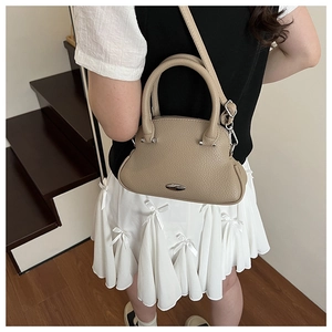 Chic beige pebble leather shell bag shown as a crossbody on a staircase background