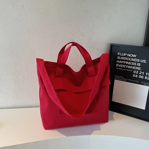 Detail view of large red canvas tote bag with side pockets on minimalist display