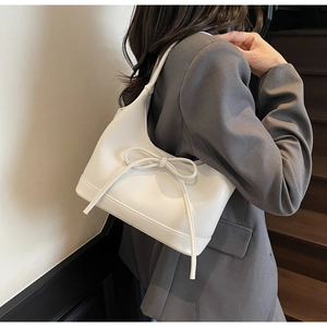 Elegant white PU leather shoulder bag with bow detail shown on a model in a gray suit