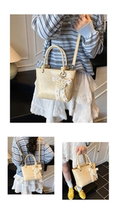 Detail of cream pleated bucket bag with lace bow and pearl heart charm accessory