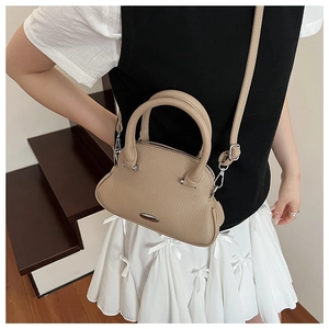 Detailed side view of khaki leather shell bag with silver hardware on model