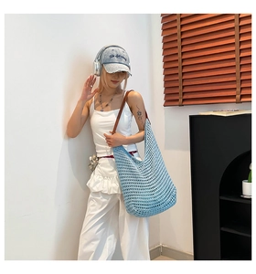 Detail of light blue woven cotton hobo bag with dark brown leather strap for summer vacation