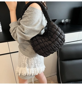 Detalle de bolso acolchado negro con textura de nube elegante y correa de hombro