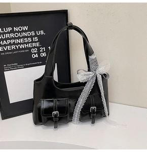 Dettaglio della borsa tote in ecopelle nera con fiocco in pizzo e fibbie argentate lucide