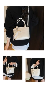 Detail of cream white pleated bucket bag with pearl bow charm and detachable strap