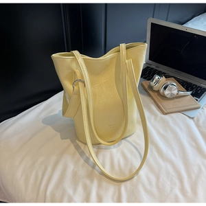 Detail of light yellow croc-embossed tote bag with silver ring hardware and shoulder straps