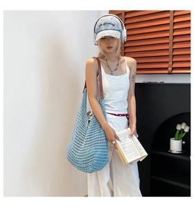 Detail of light blue woven knit hobo bag with a dark brown leather shoulder strap
