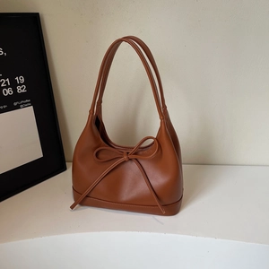 Detail of a brown vintage PU leather hobo bag with a large bow and long double handles