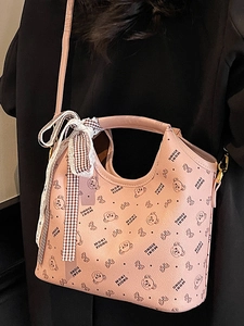 Pink printed tote bag with bear pattern and bow charm shown in a close-up shoulder carry