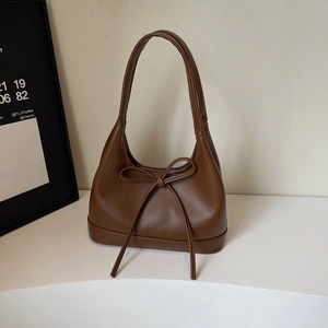 Detailed close-up of brown matte PU leather shoulder bag with bow and semi-moon shape