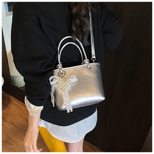 Detail of silver metallic tote bag with pearl heart pendant and lace ribbon accents