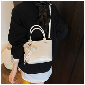 Détail du sac seau en cuir verni plissé blanc crème avec breloque perle et dentelle