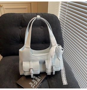 Dettaglio borsa tote azzurra in ecopelle con tasche e fiocco di nastro in pizzo bianco