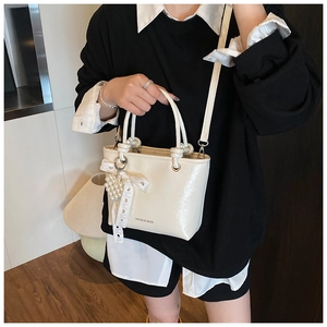 Detail of cream pleated leather bucket bag with lace bow and pearl heart charm