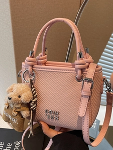 Pink woven bucket bag with knot handle and teddy bear charm for summer styling