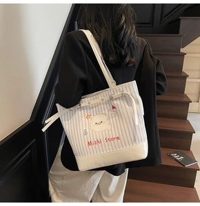 Dettaglio della borsa tote in tela a righe blu con stampa a foca e tracolla per spalla