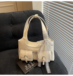 Dettaglio della borsa tote bianco crema con tasche frontali e fiocco in pizzo decorativo