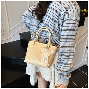 Détail du sac à main plissé crème avec breloque cœur en perles et nœud en dentelle