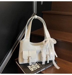 Dettaglio della borsa tote verde menta con ciondolo a fiocco su scale di legno