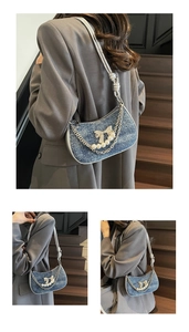 Detail of blue denim shoulder bag featuring silver metal bow, pearls and chain straps