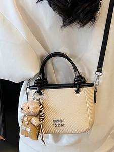 Mini woven bucket bag with black leather trim, crossbody strap and bear charm