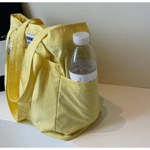 Detail of the yellow tote bag showing the functional side pocket holding a water bottle
