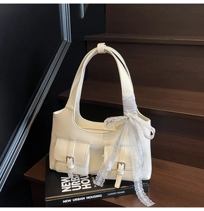 Dettaglio della borsa tote bianco crema con doppie tasche e nastro a fiocco azzurro