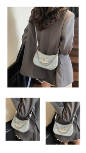 Detail of light blue pleated underarm bag with silver bow and pearl chain strap decoration