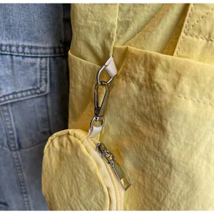 Detail of silver metal hook and matching round coin purse on yellow nylon tote bag