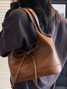Minimalist brown PU leather tote bag with elegant bow detail shown on shoulder