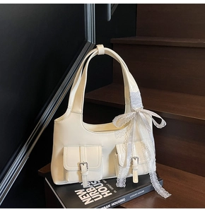 Dettaglio borsa tote color crema con tasche frontali e fiocco in pizzo su base in legno