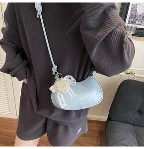 Detail of light blue crescent bag with delicate lace bow and pearl embellishment