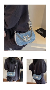 Detail of blue denim hobo bag with silver bow, pearl strap and metallic chain accents