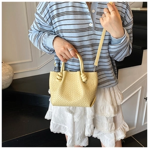 Detail of yellow woven leather bucket bag with unique knot handle and detachable strap