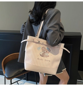 Dettaglio della borsa tote a righe rosa con illustrazione di orso e fibbia in pelle