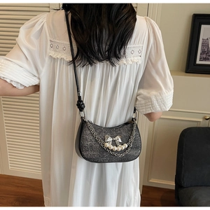 Detail of sequins crescent bag with pearl chain and silver bow charm on shoulder