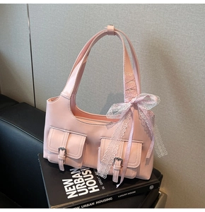 Dettaglio borsa rosa con fibbie metalliche e nastro decorativo su libri di design