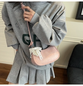 Detailed shot of pink pleated half-moon bag with lace bow and pearl pendant decoration