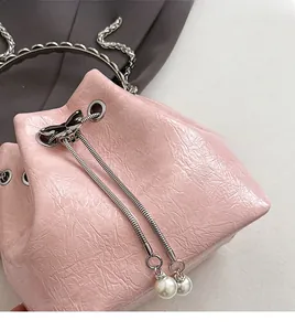 Vue détaillée du sac seau rose avec texture plissée et breloques en chaîne perle