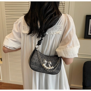 Detail of black glitter crescent shoulder bag with silver bow and pearl chain decoration