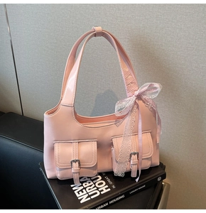 Dettaglio della borsa tote in pelle verniciata rosa con fiocco in pizzo e tasche con fibbia