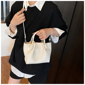 Detail showing woven texture and knotted handle of the cream bucket bag for women